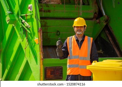 Garbage Removal Worker In Protective Clothing Working For A Public Utility Emptying Trash Container.