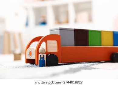 Garbage sorting play set for children. Toy truck with bright trash bins and human figure on soft carpet indoors, closeup