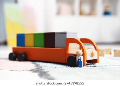Garbage sorting play set for children. Toy truck with bright trash bins and human figure on soft carpet indoors, closeup