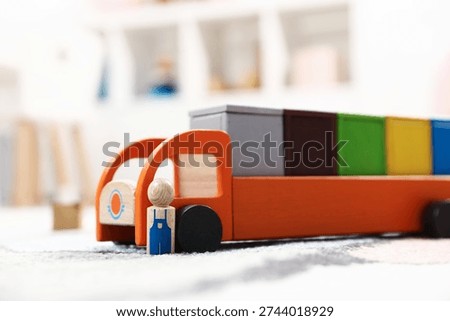 Garbage sorting play set for children. Toy truck with bright trash bins and human figure on soft carpet indoors, closeup