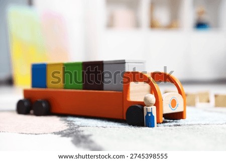 Garbage sorting play set for children. Toy truck with bright trash bins and human figure on soft carpet indoors, closeup