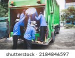 Garbage transportation workers. Scavengers take bins. Men load a metal container with garbage into a car for collecting and transporting garbage