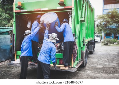 Garbage transportation workers. Scavengers take bins. Men load a metal container with garbage into a car for collecting and transporting garbage