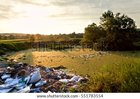 Garbage and trash around and in the water. Pullated enviroment in the sunset.