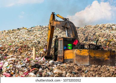 Garbage truck is working in the heat. Stink and smoke on the mountain garbage. Large garbage collection from urban and industrial areas. It is a fast-paced and difficult-to-dispose garbage.
 - Powered by Shutterstock