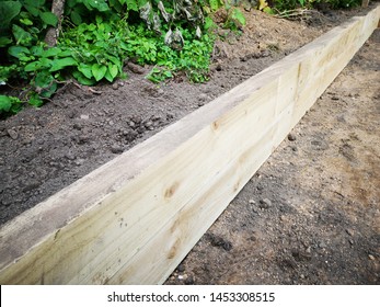 A garden being landscaped using large wooden sleepers as borders for flower and plant beds and edges of a lawn - Shutterstock ID 1453308515
