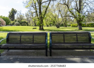 Garden bench, dark brown hardwood and green metal frame, in a public park Fitzroy Gardens Melbourne Victoria Australia - Powered by Shutterstock