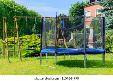Garden big Trampoline on green grass on Playground in the yard. Outdoor Trampoline with safety net with Zipper entrance. Open Jump Trampolining.