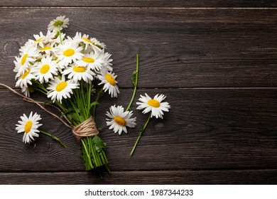 Garden camomile flowers bouquet on wooden table. Top view flat lay with copy space