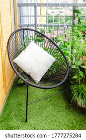 Garden Chair With Pillow On Balcony At Home In Appartment On Lawn Grass With House Plants Flowers. Garden Veranda Modern Terrace. Home Gardening, Houseplants. Rest Relaxation Place Green Oasis In City