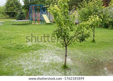 The garden and courtyard are flooded. Consequences of downpour, flood. In the background is a playground. Rainy summer in Ukraine, 2020.