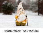 Garden dwarf with shovel in winter garden. Garden gnome on snow in yard. Ornament figurine, winter. Gnome in snow-covered curtis. Garden with fairy statuette. Troll with shovel in snowy garth