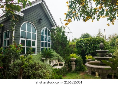 Garden And Fountain By Modern Wooden House In English Cottage Style.