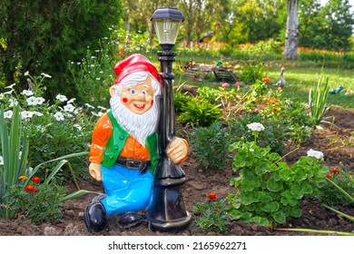 Garden gnome with a lantern in the summer garden. Ceramic statue of a garden gnome.