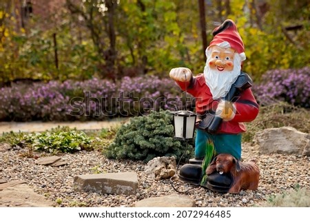 garden gnome on the background of blooming purple flowers bushes and garden