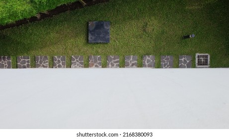 A Garden Of Green Grass, Bamboo, Square Stepping Stones, Drainage, And Lights Is Visible From Above. White Walls Can Be Used For Text Or Background Designs. Top View.