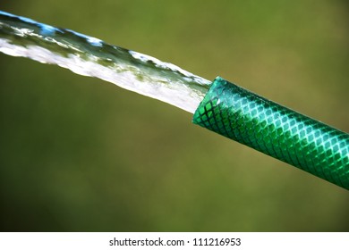 Garden hose shooting water on green background
