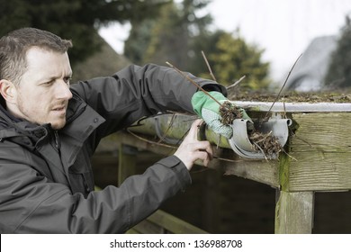 Garden And House Work. Janitor Cleaning A Roof Gutter.