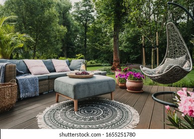 Patio jardín decorado con un sofá de mimbre escandinavo y una mesa baja