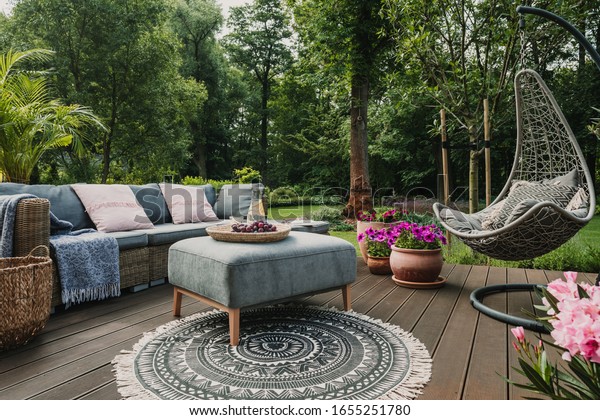 Garden patio decorated with Scandinavian wicker\
sofa and coffee table