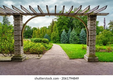 Garden Pergola With Grass Meadow And Dirt Path Between The Trees.