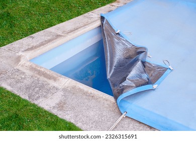 Garden pool is closed with a protective canvas when autumn arrives and prevents water evaporation and excessive soiling until the next summer season. - Shutterstock ID 2326315691