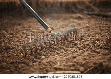 Garden rake. Black metal rake is being pulled through dry soil ready for planting. old rake on a garden bed. spring cleaning. Garden rake rakes the ground, work. Selective focus. 