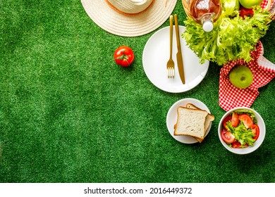 Garden Space With Picnic Basket And Food On Red Cloth. Overhead View