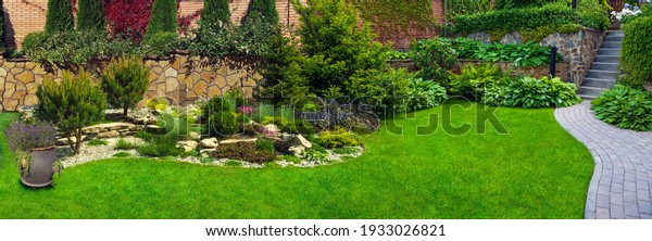 Garden stone path with grass growing up\
between the stones.Detail of a botanical\
garden.
