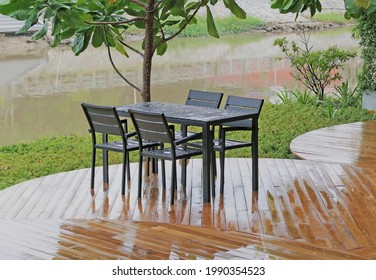 Garden tables and chairs in the rain on curved wooden decking overlooking a river view
