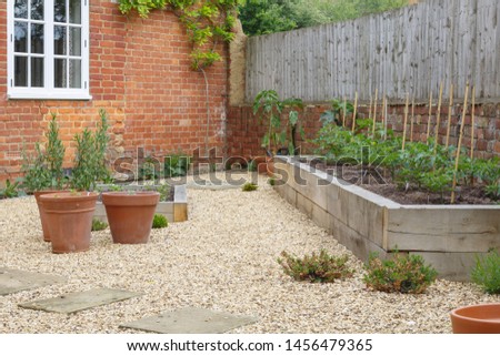 Garden with terracotta plant pots, oak sleeper raised beds and gravel