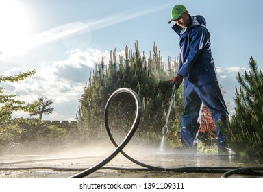 Garden Washing Maintenance. Caucasian Worker In His 30s With Pressure Washer Cleaning Brick Paths.