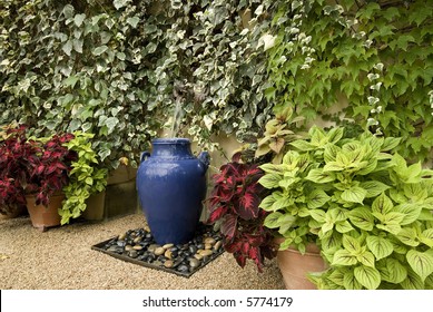 Garden Water Feature, Using A Large Blue Pot,surrounded By Wall Of Ivy And Potted Plants, Gravel Floor