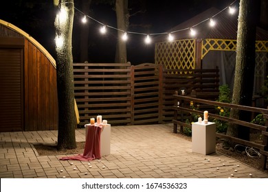 Garden with a wooden gazebo with lights, candles at night at a wedding - Powered by Shutterstock