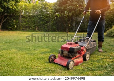 Garden work on the care of the lawn. A man mows the lawn using an electric pushing lawn mower.. cleaning concept