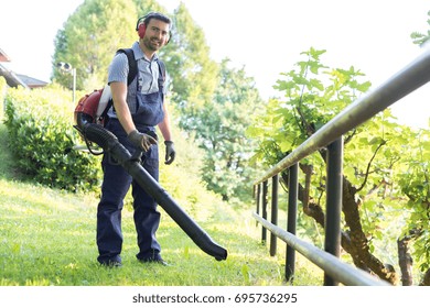 Gardener clearing up the leaves using a leaf blower tool