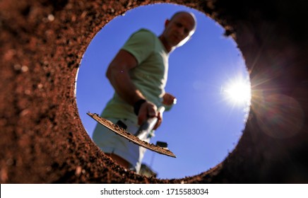 Gardener Digging With Garden Spade In Black Earth Soil. Farming, Gardening, Agriculture And People Concept. Under View Man With Shovel Digging.