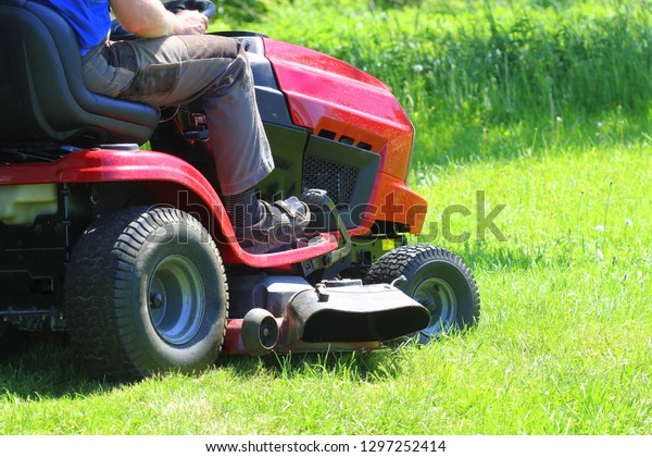 Gardener\
driving a riding lawn mower in a garden\
.