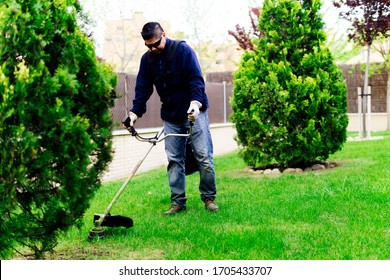 Gardener Mowing The Lawn And Tending The Garden