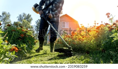 the gardener mows the grass in the garden with a grass trimmer. High quality photo