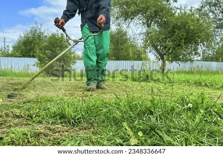 Gardener mows weeds grass. Man cutting grass in yard by using string trimmer. Worker lawn mower cutting green garden. Lawn mowing machine. Grass Trimmer and Grass Cutter. lawn maintenance service.