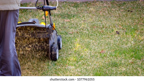 Gardener Operating Soil Aeration Machine On Grass Lawn