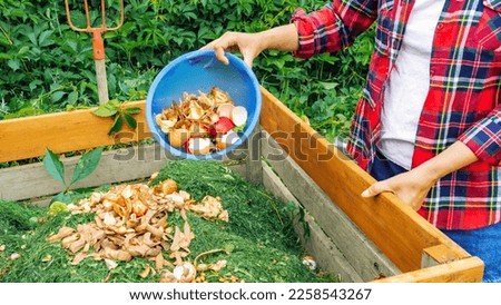 A gardener prepares compost from food organic waste in a DIY wooden compost bin. Preparation of compost from organic waste for ecological farming and gardening. Using compost to enrich the soil.