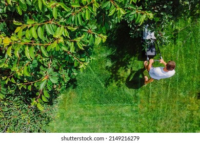 Gardener Pushing Lawn Mower For Cutting Green Grass In Garden At Summer. Aerial View.