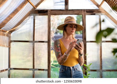 Gardener Using Her Phone In The Greenhouse