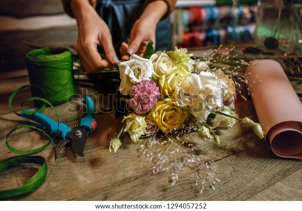 Gardener\'s in the flower shop make\
bouquet for a holiday. Family flower\'s business.  Lifestyle flower\
shop. Beautiful flower composition. Detail. Close\
up.