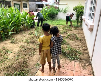 Gardeners Are Mowing Lawn In Home Garden And Two Children Are Watching With Pleasure