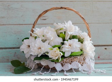 Gardenia Bouquet In The Wicker Basket Put On Wooden Table Against Wooden Back Drop.