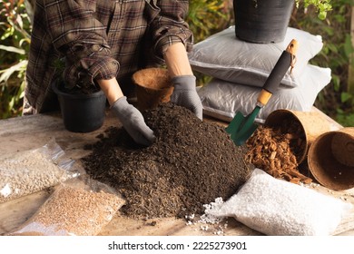 Gardening concept. A young woman mixes potting soil, prepares the soil for planting vegetables and herbs in the house, mixes potting soil, perlite, vermiculite, peat, worm, coconut flakes, rice husk.  - Shutterstock ID 2225273901