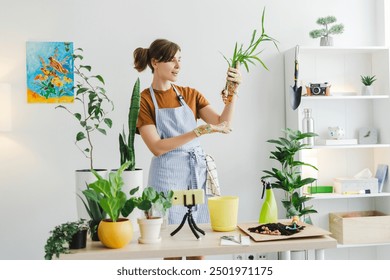 Gardening expert wearing gloves is showing plant roots while recording an online gardening class surrounded by plants - Powered by Shutterstock